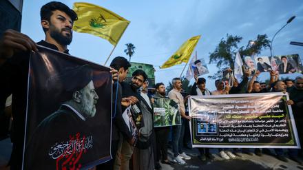 Iraqis carry portraits of Iran's late president Ebrahim Raisi outside the Iranian embassy in Baghdad during a condolences service on May 20, 2024 for the president and his entourage, who were killed in a helicopter crash in Iran the previous day. (Photo by AHMAD AL-RUBAYE / AFP)