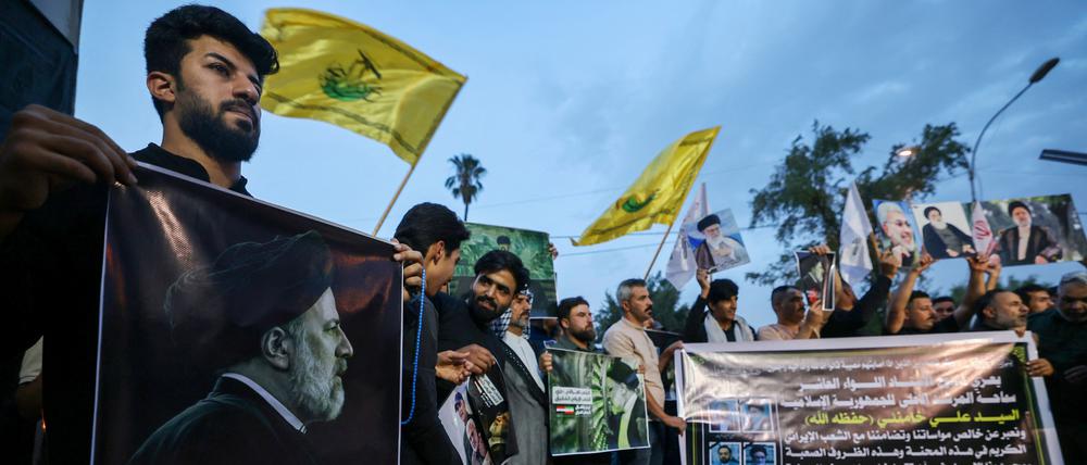 Iraqis carry portraits of Iran's late president Ebrahim Raisi outside the Iranian embassy in Baghdad during a condolences service on May 20, 2024 for the president and his entourage, who were killed in a helicopter crash in Iran the previous day. (Photo by AHMAD AL-RUBAYE / AFP)