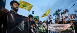 Iraqis carry portraits of Iran's late president Ebrahim Raisi outside the Iranian embassy in Baghdad during a condolences service on May 20, 2024 for the president and his entourage, who were killed in a helicopter crash in Iran the previous day. (Photo by AHMAD AL-RUBAYE / AFP)