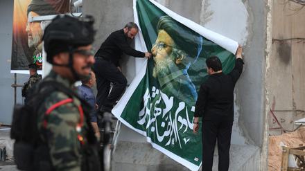 Ein Plakat zum Gedenken an Raisi wird augehängt.