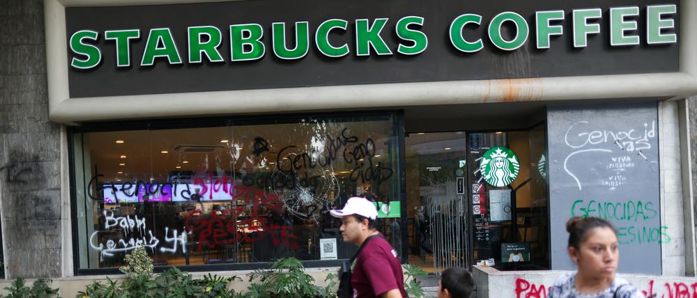 Vandalismus in Mexiko City. Passanten gehen an einem von Demonstranten beschmierten Café von Starbucks vorbei.  