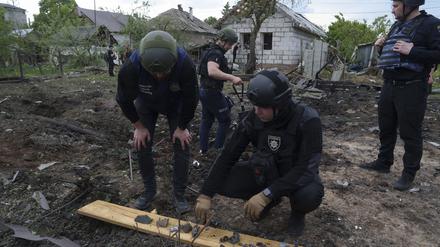 Ein ukrainischer Polizeibeamter und ein Staatsanwalt für Kriegsverbrechen inspizieren Bruchstücke einer Gleitbombe vor einem beschädigten Haus nach einem russischen Luftangriff auf ein Wohnviertel. 