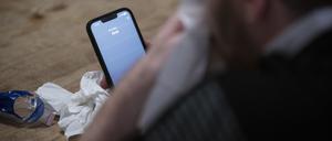 Ein Mann hält ein Taschentuch in einer Hand und ein Telefon mit dem Schriftzug „Arzt“ in der Anderen.