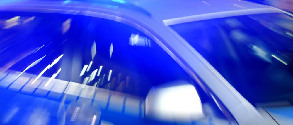 Ein Streifenwagen der Polizei steht mit eingeschaltetem Blaulicht auf der Straße.