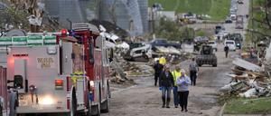 Menschen gehen in Greenfield, Iowa, eine Straße entlang, vorbei an Schäden nach einem Tornado. 