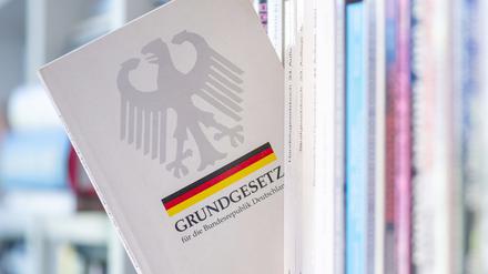 Ein Grundgesetz steckt in einem Bücherregal (Symbolfoto).