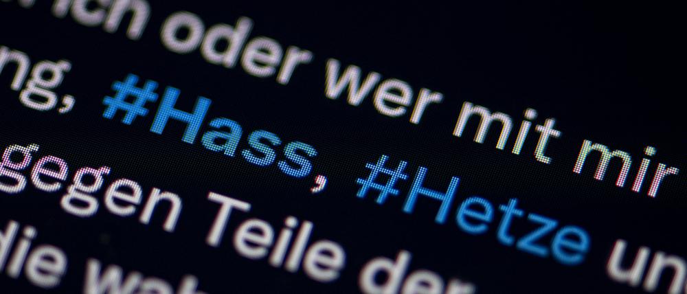 Auf dem Bildschirm eines Smartphones sieht man die Hashtags Hass und Hetze in einem Twitter-Post.