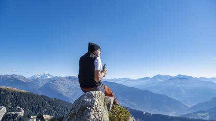 Ein älterer Mann sitzt auf einem Felsen an einem sonnigen Tag im Vanoise-Nationalpark, Frankreich.