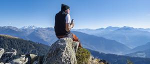 Ein älterer Mann sitzt auf einem Felsen an einem sonnigen Tag im Vanoise-Nationalpark, Frankreich.