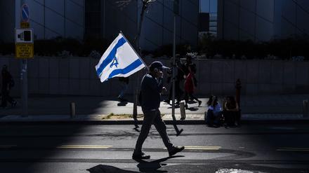 Ein israelischer Demonstrant hält eine Nationalflagge während eines regierungskritischen Protests. 