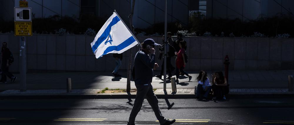 Ein israelischer Demonstrant hält eine Nationalflagge während eines regierungskritischen Protests. 