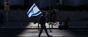 Ein israelischer Demonstrant hält eine Nationalflagge während eines regierungskritischen Protests. 