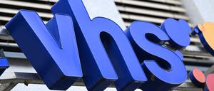 Die blauen Buchstaben „vhs“ stehen an der Fassade einer Volkshochschule,