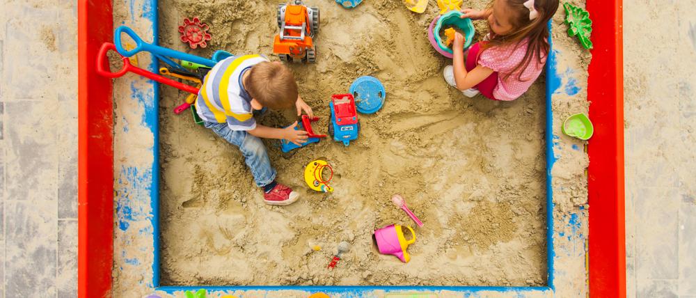 Kinder spielen in einem Sandkasten.