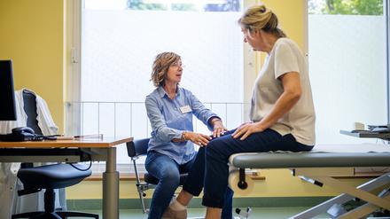 Eine Ärztin untersucht das Knie ihrer Patientin.