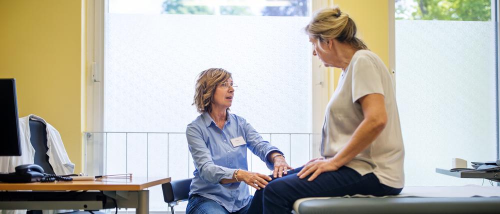 Eine Ärztin untersucht das Knie ihrer Patientin.