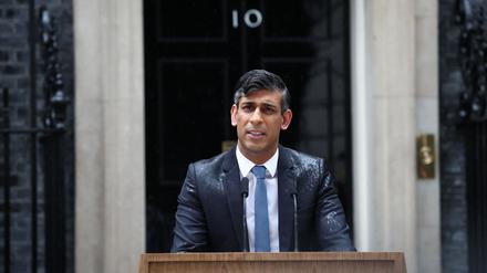 Premierminister Rishi Sunak steht im Regen.