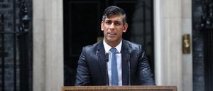 Premierminister Rishi Sunak steht im Regen.