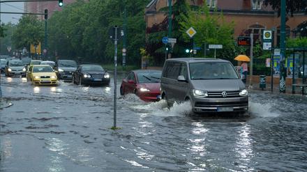 22.05.2024, Brandenburg, Potsdam: Autos fahren im Schritttempo durch die überflutete Zeppelinstraße. Starkregen hat am späten Nachmittag in Potsdam die Kreuzung Zeppelinstraße/Geschwister-Scholl-Straße unter Wasser gesetzt. (zu dpa: «Unwetter ohne große Schäden · Straßen überflutet und Äste abgebrochen») Foto: Georg Moritz/dpa +++ dpa-Bildfunk +++U