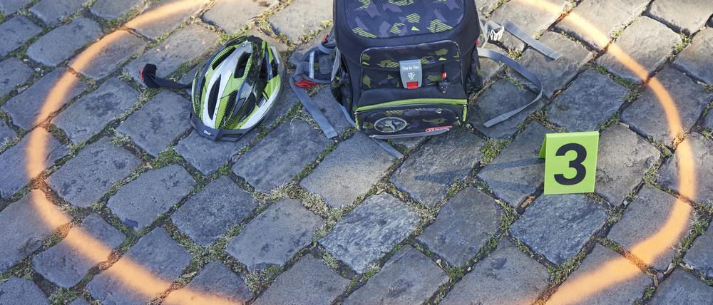 Helm und Ranzen auf dem Boden: nachgestellte Situation eines Verkehrsunfalls.