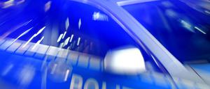 Ein Streifenwagen der Polizei steht mit eingeschaltetem Blaulicht auf der Straße. 