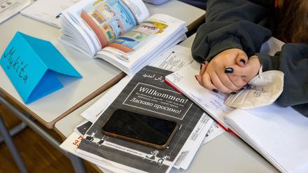 Ein Mädchen aus der Ukraine sitzt mit ihrem Unterrichtsmaterial in einer Klasse. 