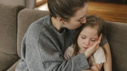 Eine Mutter küsst ihre Tochter auf den Kopf.