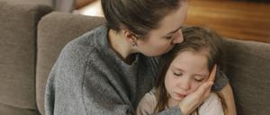 Eine Mutter küsst ihre Tochter auf den Kopf.