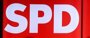 Mikrofone stehen vor einer leuchteten Wand mit dem Logo der SPD.