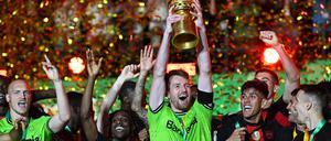 Leverkusens Torhüter Lukas Hradecky (M) hält den Pokal jubelnd hoch während seine Teamkollegen feiern.