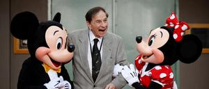 Der Songwriter Richard M. Sherman posiert mit Micky und Minnie Maus.