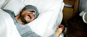 Ein schlafender Mann liegt im Bett und ringt mit offenem Mund um Luft.