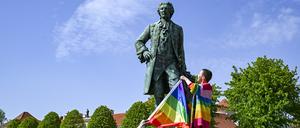 Am Denkmal von Kronprinz Friedrich zeigen der Politiker Freke Over und Marie von der Vorbereitungsgruppe des ersten „Christopher Street Day“ (CSD) in Rheinsberg die Regenbogenfahne.