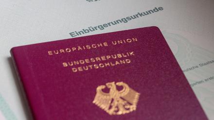Eine Einbürgerungsurkunde der Bundesrepublik Deutschland und ein deutscher Reisepass liegen auf einem Tisch.