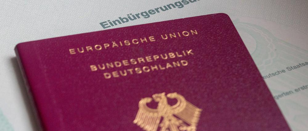 Eine Einbürgerungsurkunde der Bundesrepublik Deutschland und ein deutscher Reisepass liegen auf einem Tisch. 