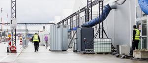 Ein Mitarbeiter einer Sicherheitsfirma geht vor den Unterkunftskomplexen im Ankunftszentrum Tegel entlang.