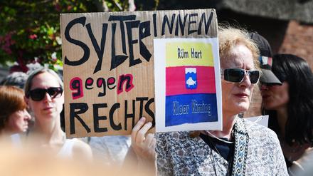 „SylterInnen gegen Rechts“ steht auf einem Schild, das eine Frau bei einer Mahnwache in der Hand hält.