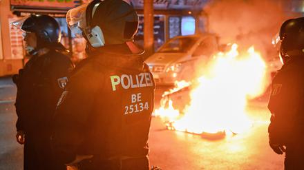 Polizeibeamte stehen auf der Sonnenallee in Neukölln an zwei in Brand gesetzten Mülltonnen. In der Sonnenallee kommt es bei propalästinensischen Versammlungen häufiger zu gewalttätigen Auseinandersetzungen. (Symbolbild)