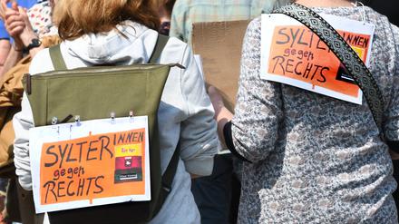 Sylter gegen Rechts!· steht auf Plakaten, die zwei Frauen bei einer Mahnwache am Sonntag auf Sylt auf ihre Rücken geheftet haben.