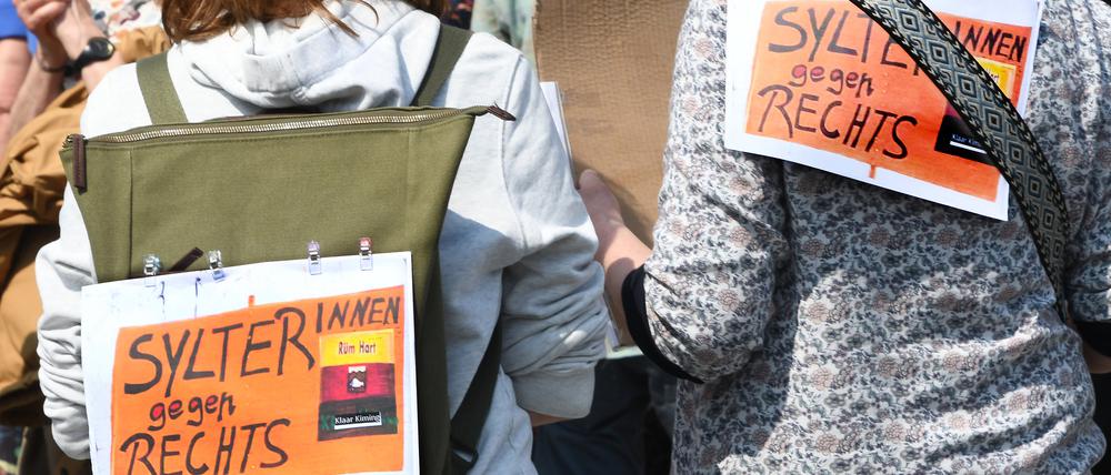 Sylter gegen Rechts!· steht auf Plakaten, die zwei Frauen bei einer Mahnwache am Sonntag auf Sylt auf ihre Rücken geheftet haben.