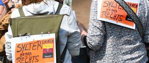 Sylter gegen Rechts!· steht auf Plakaten, die zwei Frauen bei einer Mahnwache am Sonntag auf Sylt auf ihre Rücken geheftet haben.