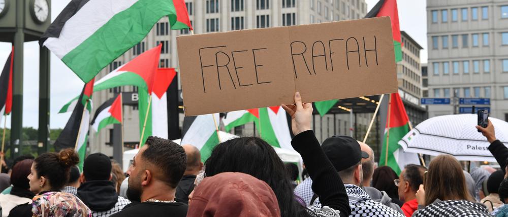 30.05.2024, Berlin: Teilnehmer einer propalästinensischen Demonstration zeigen palästinensische Flaggen und ein Schild mit der Aufschrift "Free Rafah" am Potsdamer Platz. Foto: Paul Zinken/dpa +++ dpa-Bildfunk +++