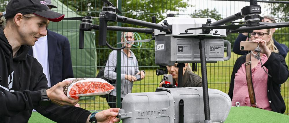 Eine Drohne wird bei der Betriebseröffnung vom Drohnen-Lieferservice ·Marktschwalbe· mit einem Bäckerbrot beladen.