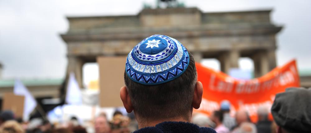 Ein Teilnehmer mit Kippa der Kundgebung «Steh auf! Nie wieder Judenhass!» des Zentralrats der Juden in Deutschland steht vor dem Brandenburger Tor in Berlin.
