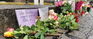 Mannheim: Kerzen und Blumen stehen am Tatort auf dem Marktplatz neben einem Schild „Wer Polizisten angreift, greift uns alle an!“. 