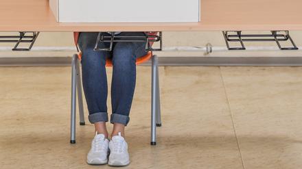 Eine Wählerin sitzt im Wahllokal in einer Grundschule hinter einer Wahlkabine und füllt ihre Stimmzettel für die Europawahl und die Kommunalwahl aus.  