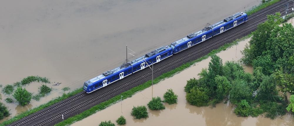 Ein Zug fährt über den höher gelegenen Bahndamm von Meckenbeuren, wo das Hochwasser des Flusses Schussen Teile des Ortes in Baden-Württemberg überschwemmt.