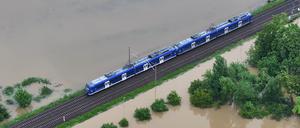 Ein Zug fährt über den höher gelegenen Bahndamm von Meckenbeuren, wo das Hochwasser des Flusses Schussen Teile des Ortes in Baden-Württemberg überschwemmt.