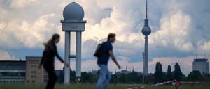 Zwei Inline-Skater fahren bei warmen Temperaturen vor der Kulisse des Berliner Fernsehturms über das Tempelhofer Feld. 