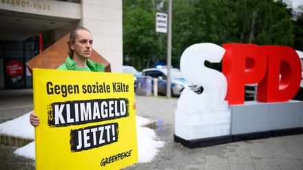 Ein Aktivist hält bei einer Protestaktion der Umweltschutz-Organisation Greenpeace vor der SPD-Zentrale ein Schild mit der Aufschrift „Gegen soziale Kälte - Klimageld jetzt!“. Greenpeace-Aktivisten haben vor der SPD-Zentrale in Kreuzberg etwa eine Tonne Eis ausgeschüttet und ein gefrorenes „S“ vom SPD-Schriftzug aufgestellt, um für die Einführung des Klimagelds zu demonstrieren.